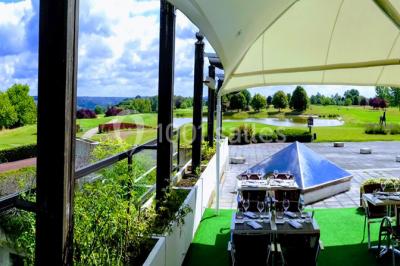 Salle de réception décorée avec des tables rondes, nappes blanches et chaises ornées de nœuds colorés.