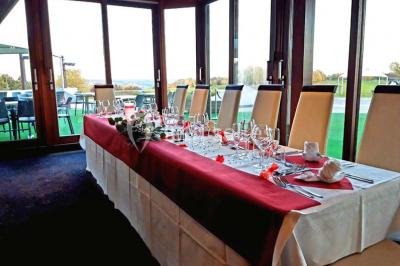 Salle de réception décorée avec des tables rondes, nappes blanches et chaises ornées de nœuds colorés.