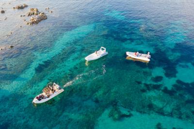 Barques traditionnelles sur une plage bordée de végétation, avec vue sur la mer et des montagnes à l'horizon.