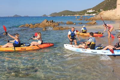 Barques traditionnelles sur une plage bordée de végétation, avec vue sur la mer et des montagnes à l'horizon.