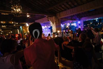 Miniature Location salle Vérargues (Hérault) - Château de Pouget #13 Salle en pierre avec arches, tables décorées et stands alignés, éclairage chaleureux créant une ambiance conviviale.