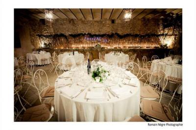 Miniature Location salle Vérargues (Hérault) - Château de Pouget #9 Salle en pierre avec arches, tables décorées et stands alignés, éclairage chaleureux créant une ambiance conviviale.