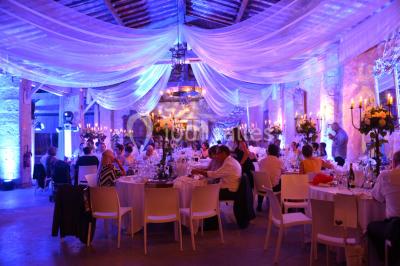 Miniature Location salle Vérargues (Hérault) - Château de Pouget #11 Salle en pierre avec arches, tables décorées et stands alignés, éclairage chaleureux créant une ambiance conviviale.