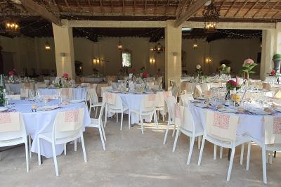 Miniature Location salle Vérargues (Hérault) - Château de Pouget #19 Salle en pierre avec arches, tables décorées et stands alignés, éclairage chaleureux créant une ambiance conviviale.