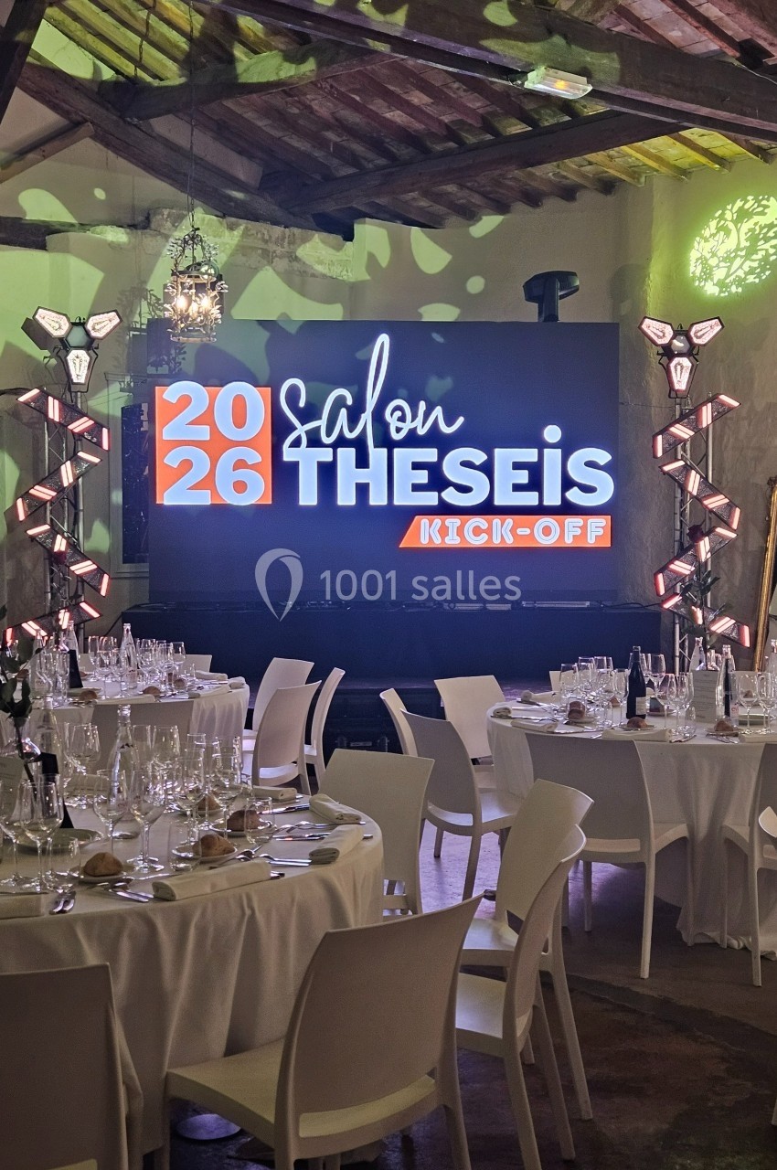 Salle décorée avec des tables dressées et un écran affichant ’2026 Salon THESEIS Kick-Off’.