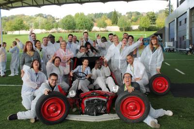 Des personnes debout en cercle dans une grande salle colorée, participant à une activité collective.