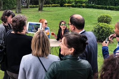 Des personnes debout en cercle dans une grande salle colorée, participant à une activité collective.