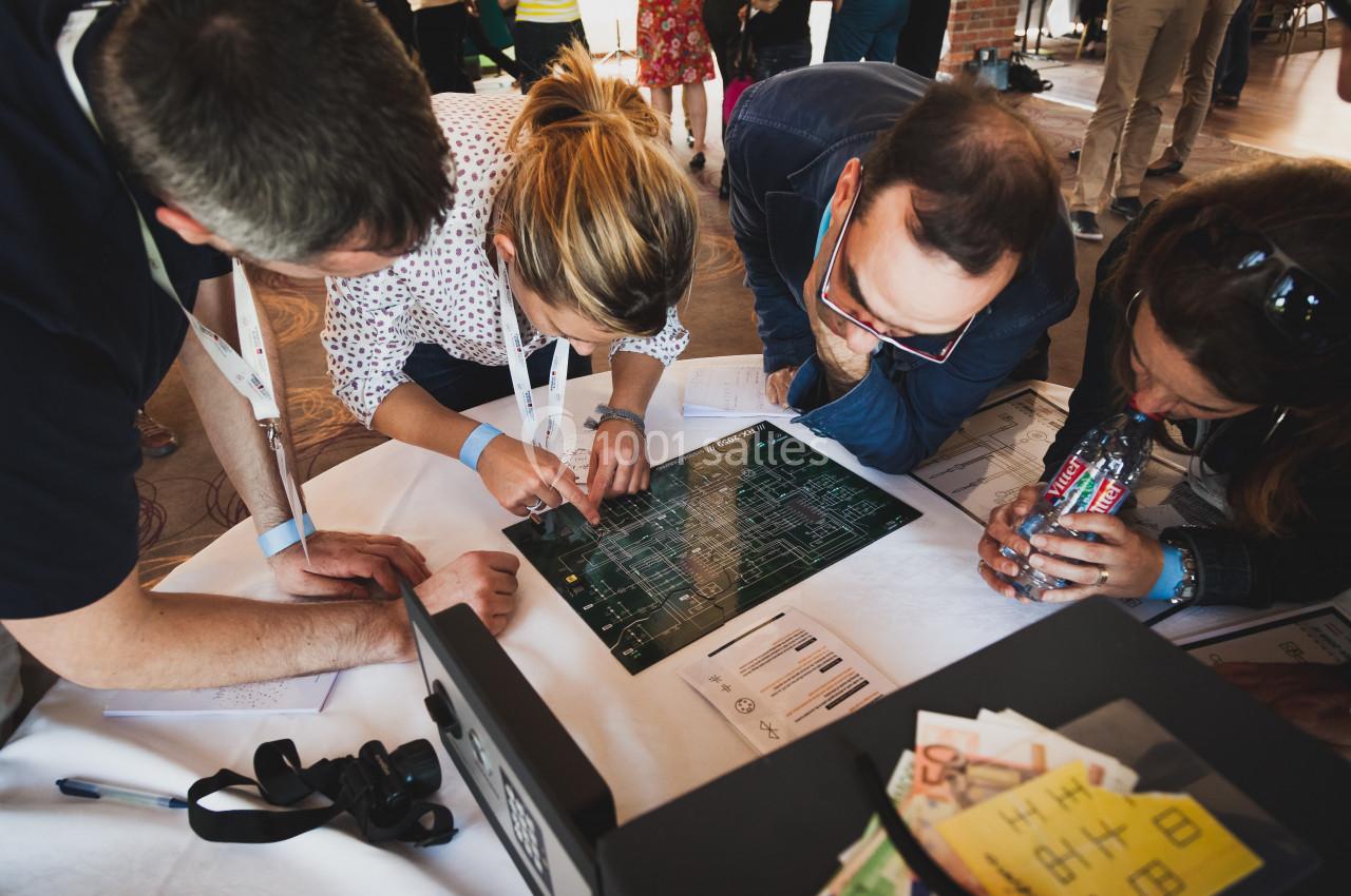 Des personnes collaborent autour d'une table, examinant un plan ou un schéma électronique.