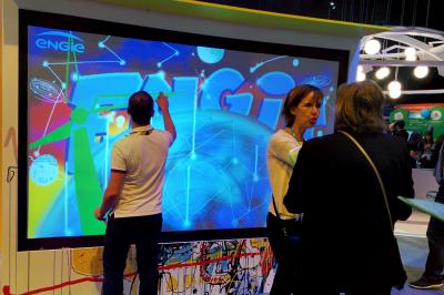 Des personnes debout en cercle dans une grande salle colorée, participant à une activité collective.