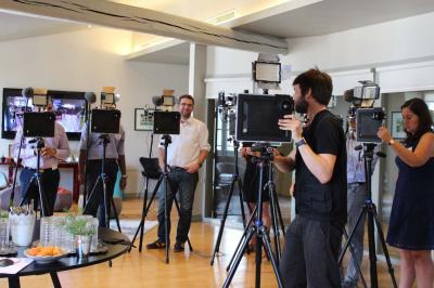 Des personnes debout en cercle dans une grande salle colorée, participant à une activité collective.