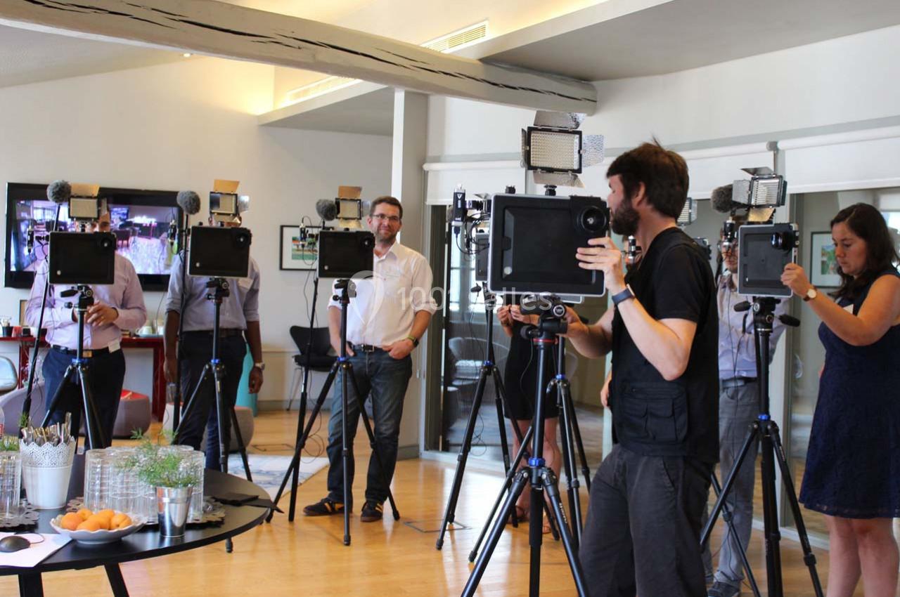 Des personnes debout dans une salle, utilisant des tablettes montées sur des trépieds équipés de micros et de lumières.