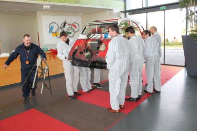 Des personnes debout en cercle dans une grande salle colorée, participant à une activité collective.