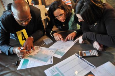 Des personnes debout en cercle dans une grande salle colorée, participant à une activité collective.