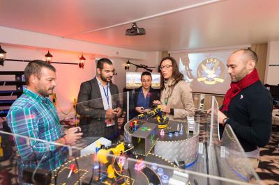 Des personnes debout en cercle dans une grande salle colorée, participant à une activité collective.