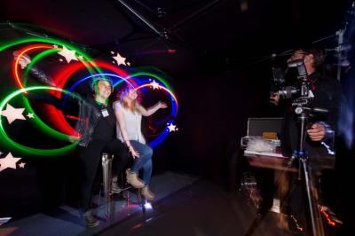 Des personnes debout en cercle dans une grande salle colorée, participant à une activité collective.