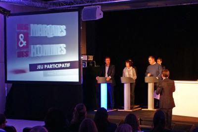 Des personnes debout en cercle dans une grande salle colorée, participant à une activité collective.