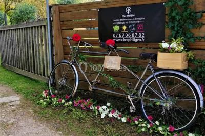 Un tandem décoré de fleurs et d'une caisse en bois, appuyé contre une clôture en bois avec un panneau publicitaire.