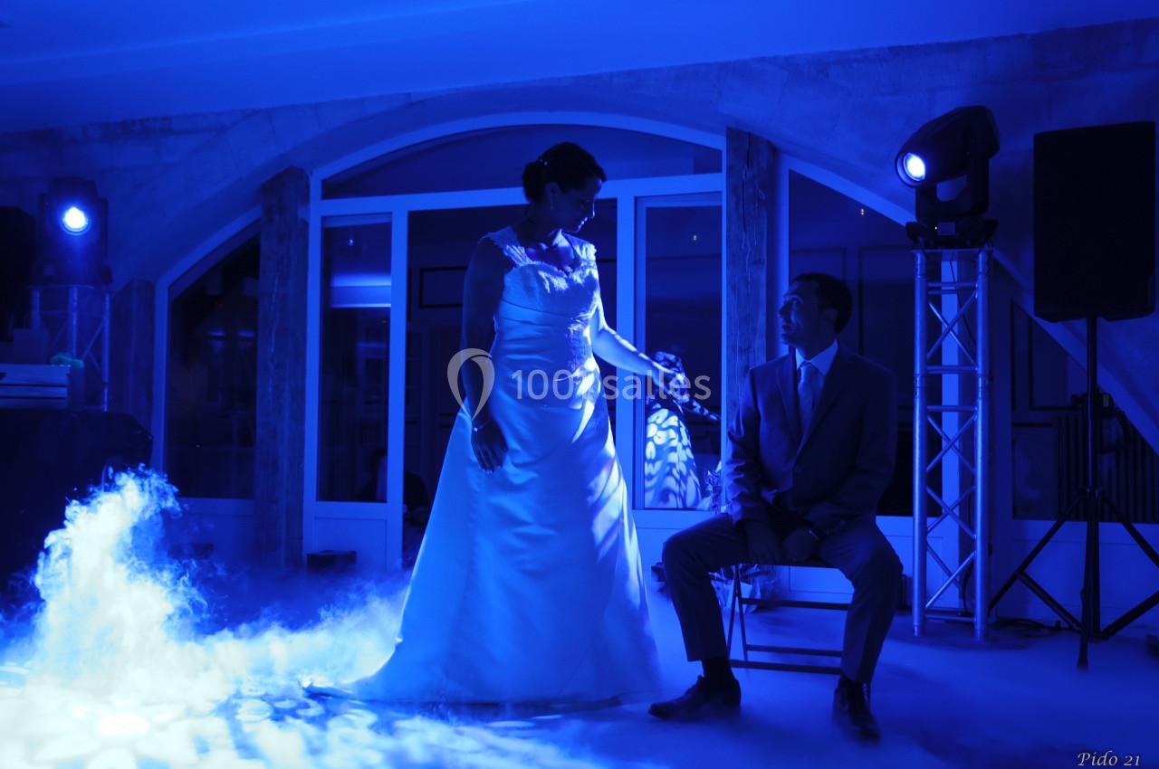 Une mariée en robe blanche et un homme en costume assis, éclairés par une lumière bleue dans une ambiance festive.
