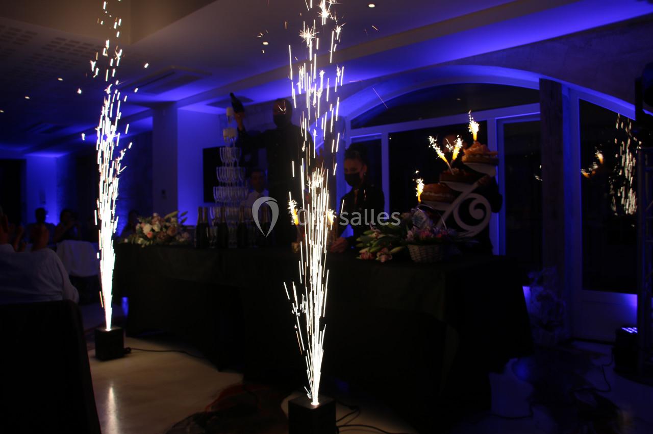 Effets pyrotechniques illuminant une salle sombre lors d'une célébration, avec des décorations et des desserts en arrière…