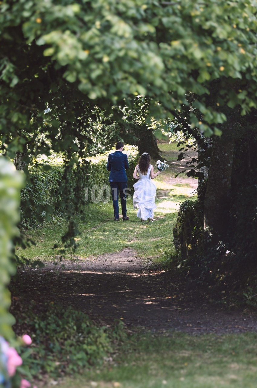 Un couple marche sur un sentier verdoyant, entouré d'arbres et de végétation.