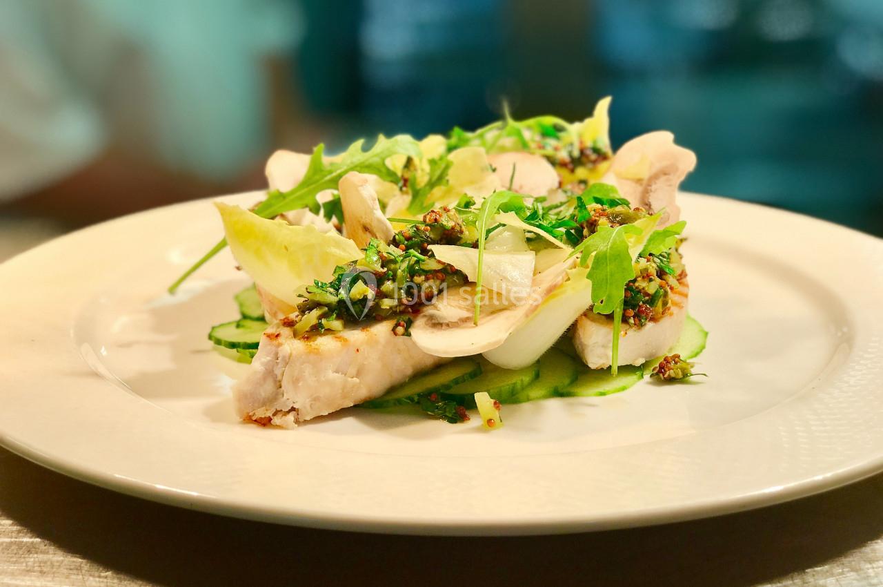 Location salle Gressy (Seine-et-Marne) - Le Manoir de Gressy #16 Assiette de poisson blanc garni de légumes verts, herbes fraîches et sauce aux graines, servie sur une table lumineuse.