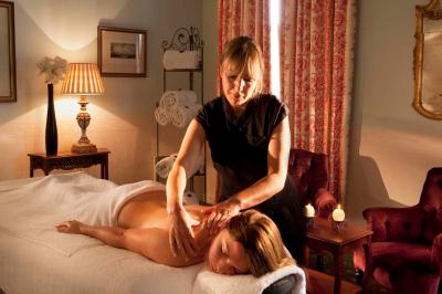 Miniature Location salle Gressy (Seine-et-Marne) - Le Manoir de Gressy #29 Une femme reçoit un massage sur une table dans une pièce chaleureuse avec des rideaux, des bougies et une lumière tamisée.