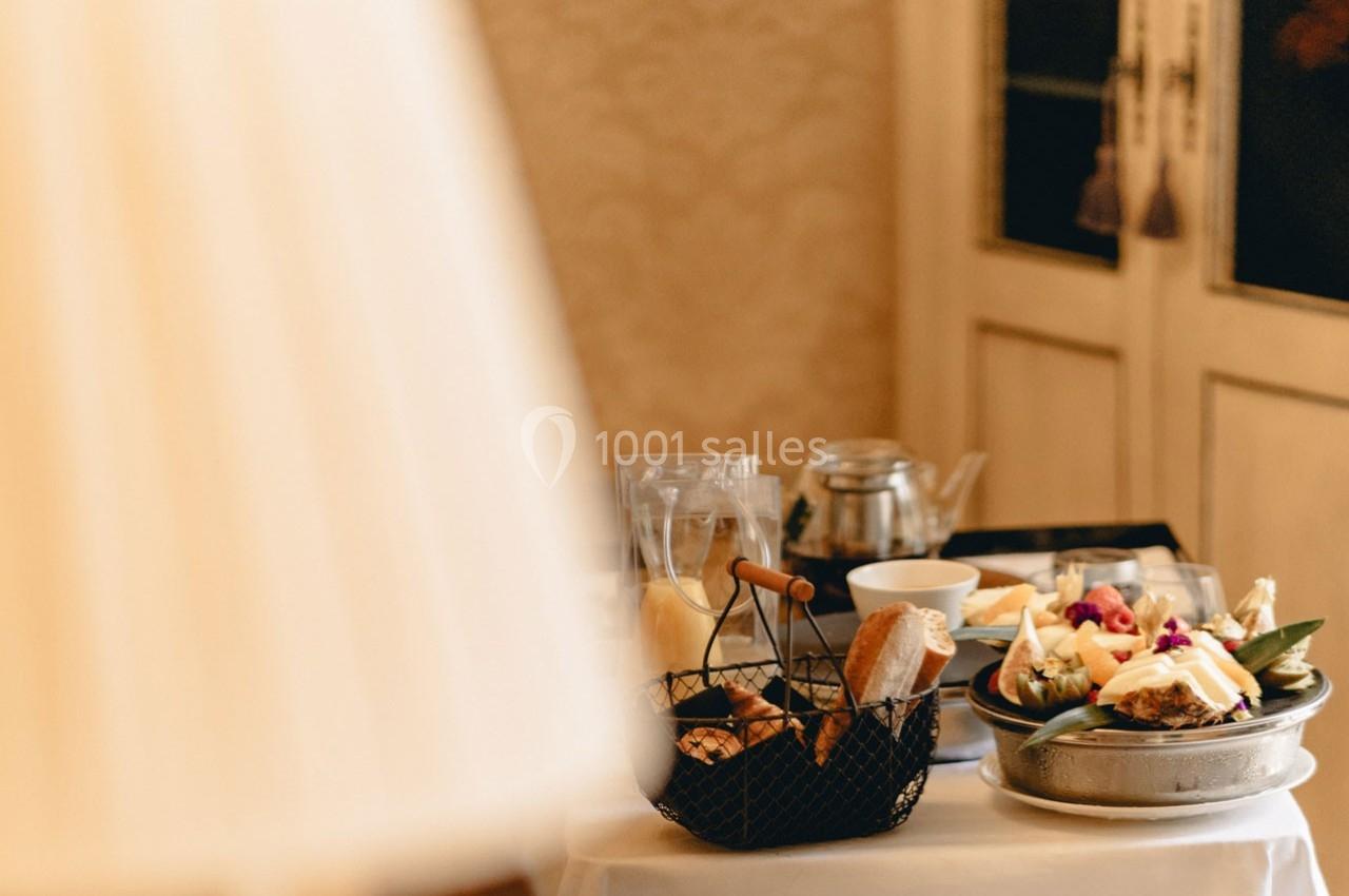 Location salle Gressy (Seine-et-Marne) - Le Manoir de Gressy #17 Petit-déjeuner servi sur une table avec viennoiseries, fruits, théière et assiettes, dans un décor chaleureux.