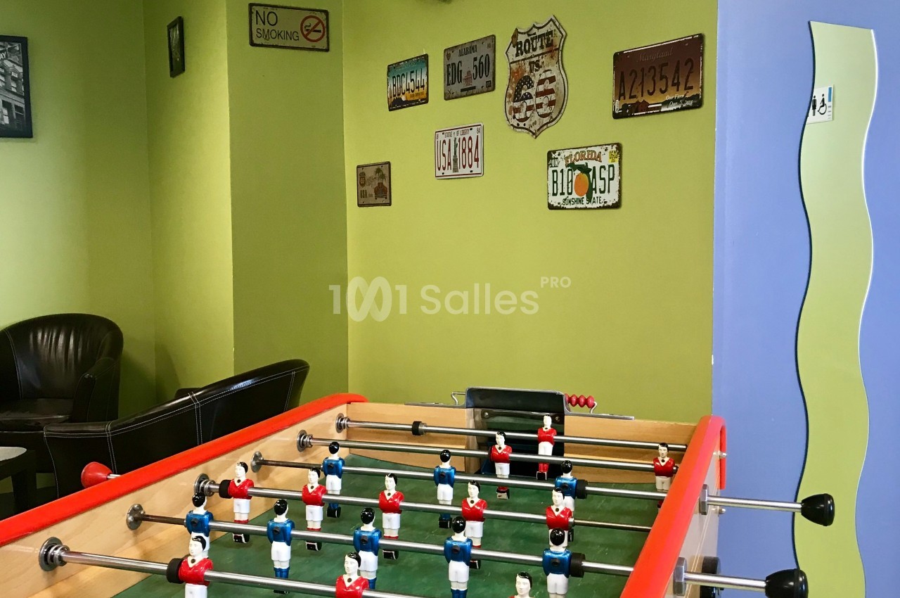 Baby-foot dans une salle décorée de plaques vintage accrochées sur des murs verts et bleus.