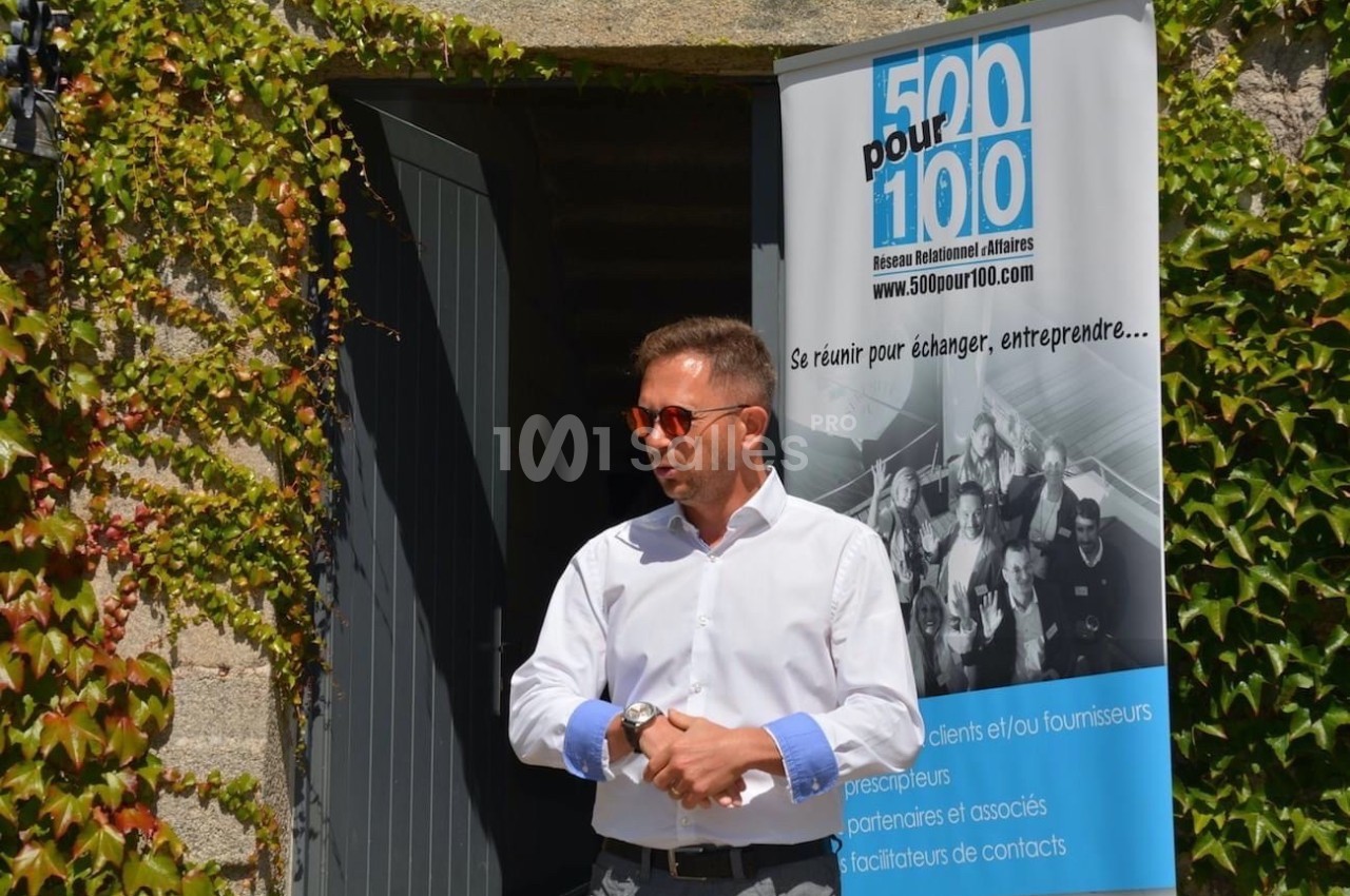 Un homme en chemise blanche parle devant une porte ouverte, près d'une bannière d'un réseau professionnel.