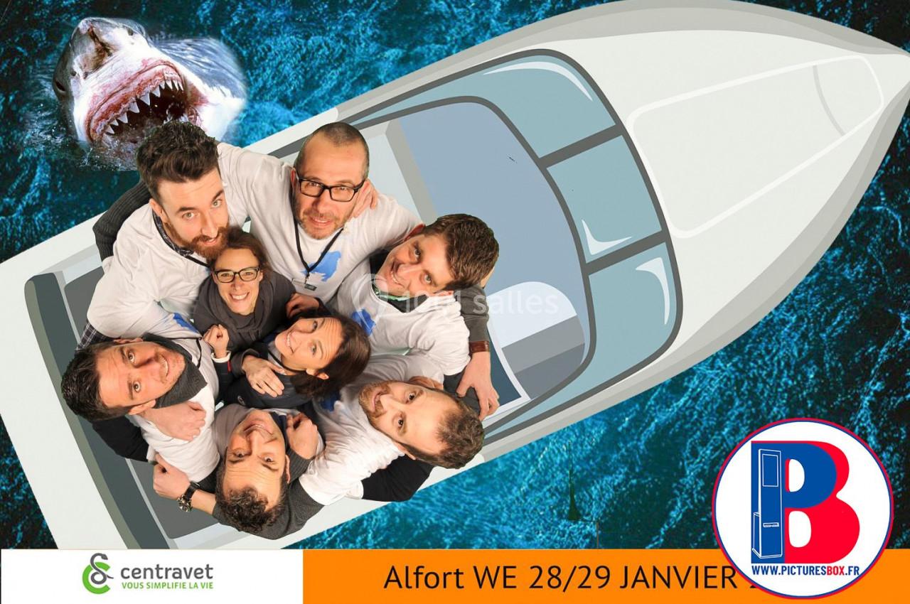 Un groupe de personnes souriantes posant sur un bateau vu de dessus, avec un requin en arrière-plan dans l'eau.