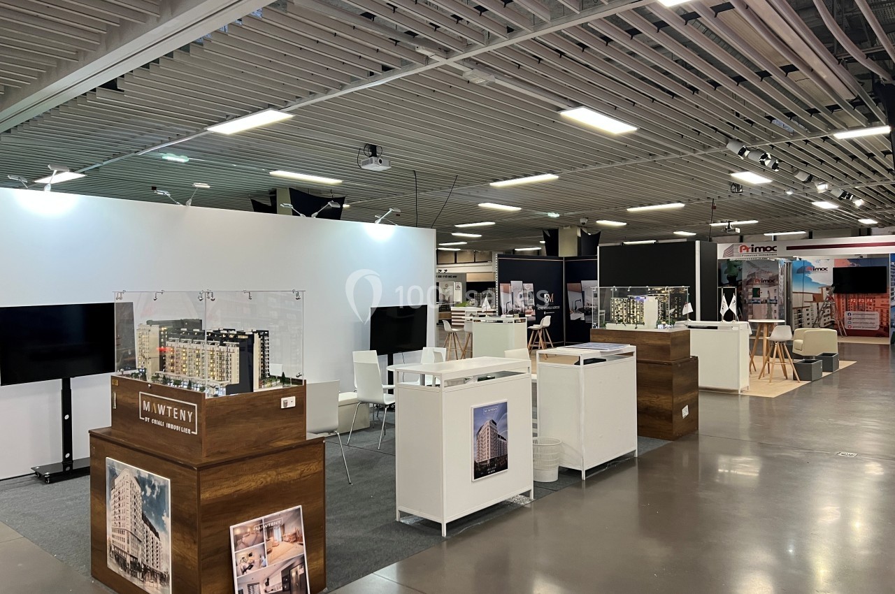 Stands d'exposition dans un espace intérieur avec maquettes architecturales et panneaux d'information.