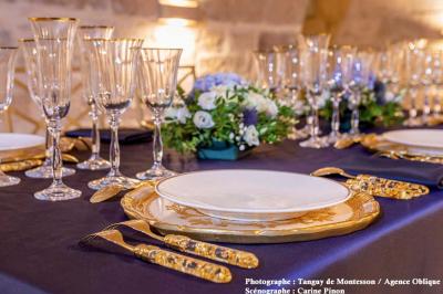 Espace salon moderne avec fauteuils verts, tables basses en bois, tapis rond clair, plantes et décorations murales.