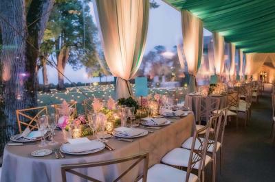 Une voiture de luxe bleue exposée dans un showroom, un homme examine l'intérieur par la portière ouverte.