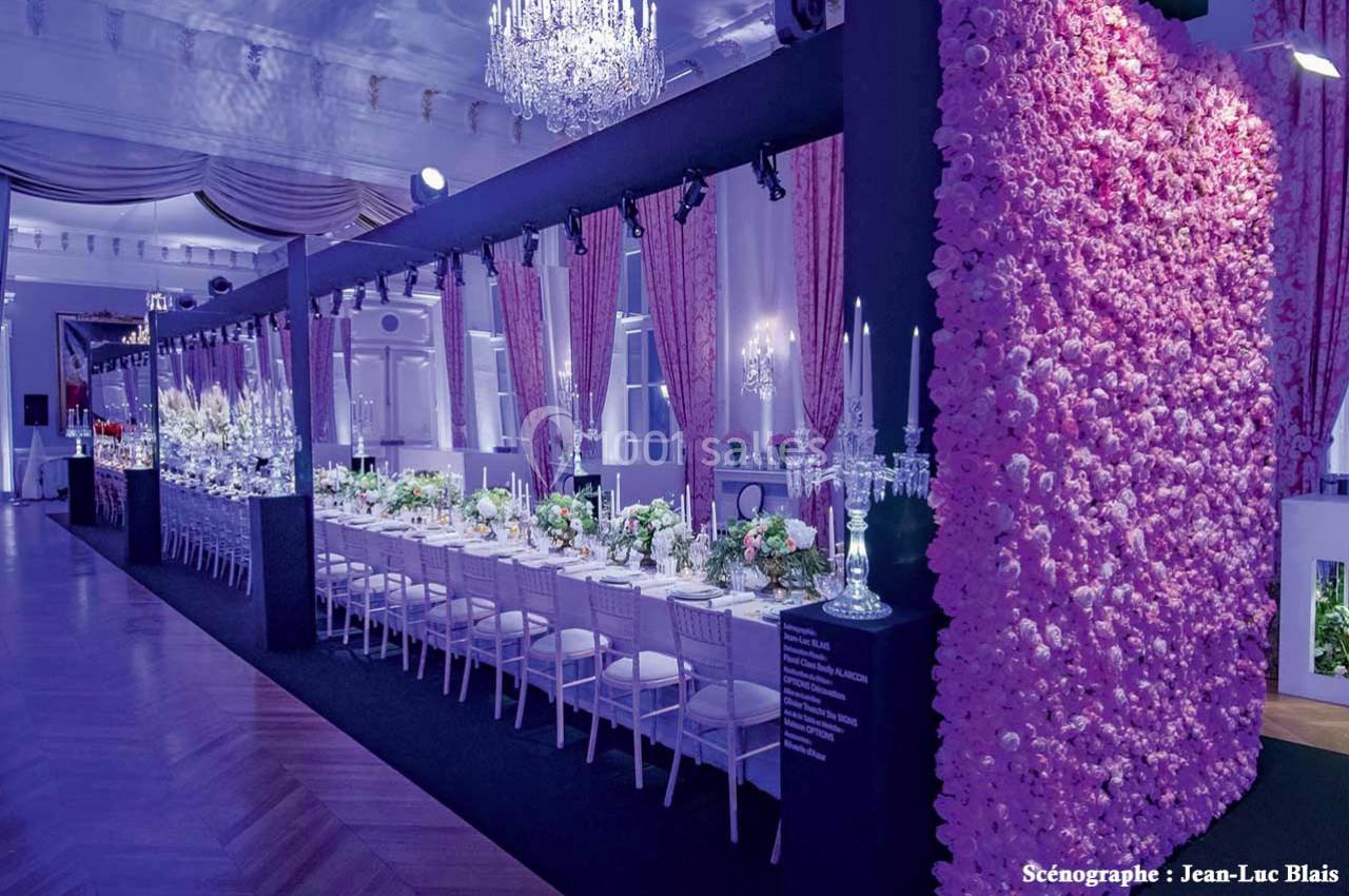 Salle de réception élégante avec une longue table décorée de fleurs et un mur recouvert de roses roses.