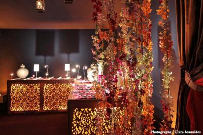 Salle lumineuse avec parquet en bois, table ronde dressée avec nappe rouge et chaises, décorée de moulures au plafond.