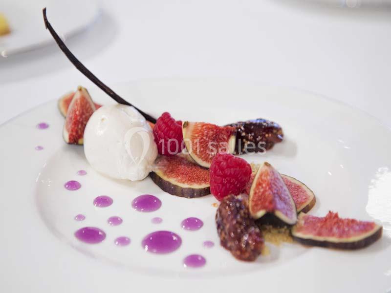 Assiette de dessert composée de figues fraîches, framboises, glace vanille, dattes et décorée de gouttes de coulis violet.
