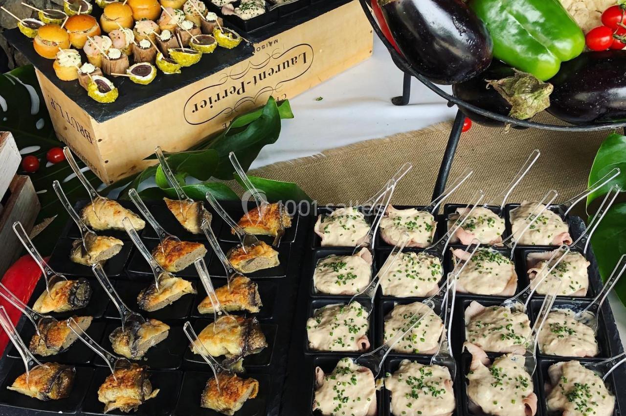 Plateau de bouchées apéritives variées disposées sur des caisses en bois, entourées de légumes frais.