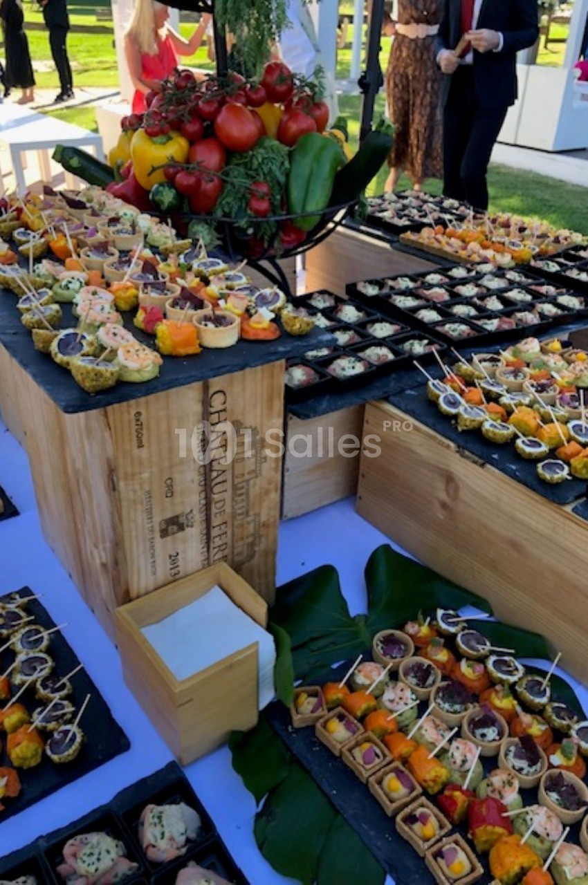 Buffet en plein air avec une présentation soignée de bouchées apéritives variées sur des plateaux et caisses en bois.