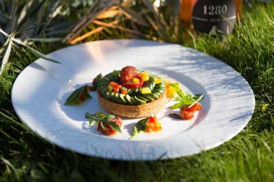 Personne utilisant une trancheuse rouge pour couper de la charcuterie dans un environnement professionnel.