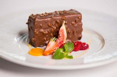 Personne utilisant une trancheuse rouge pour couper de la charcuterie dans un environnement professionnel.