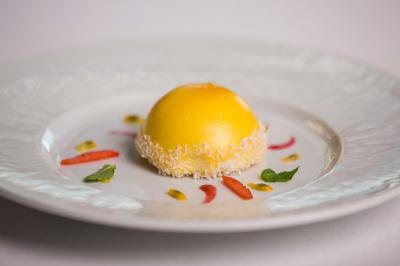 Personne utilisant une trancheuse rouge pour couper de la charcuterie dans un environnement professionnel.