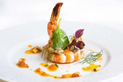 Personne utilisant une trancheuse rouge pour couper de la charcuterie dans un environnement professionnel.