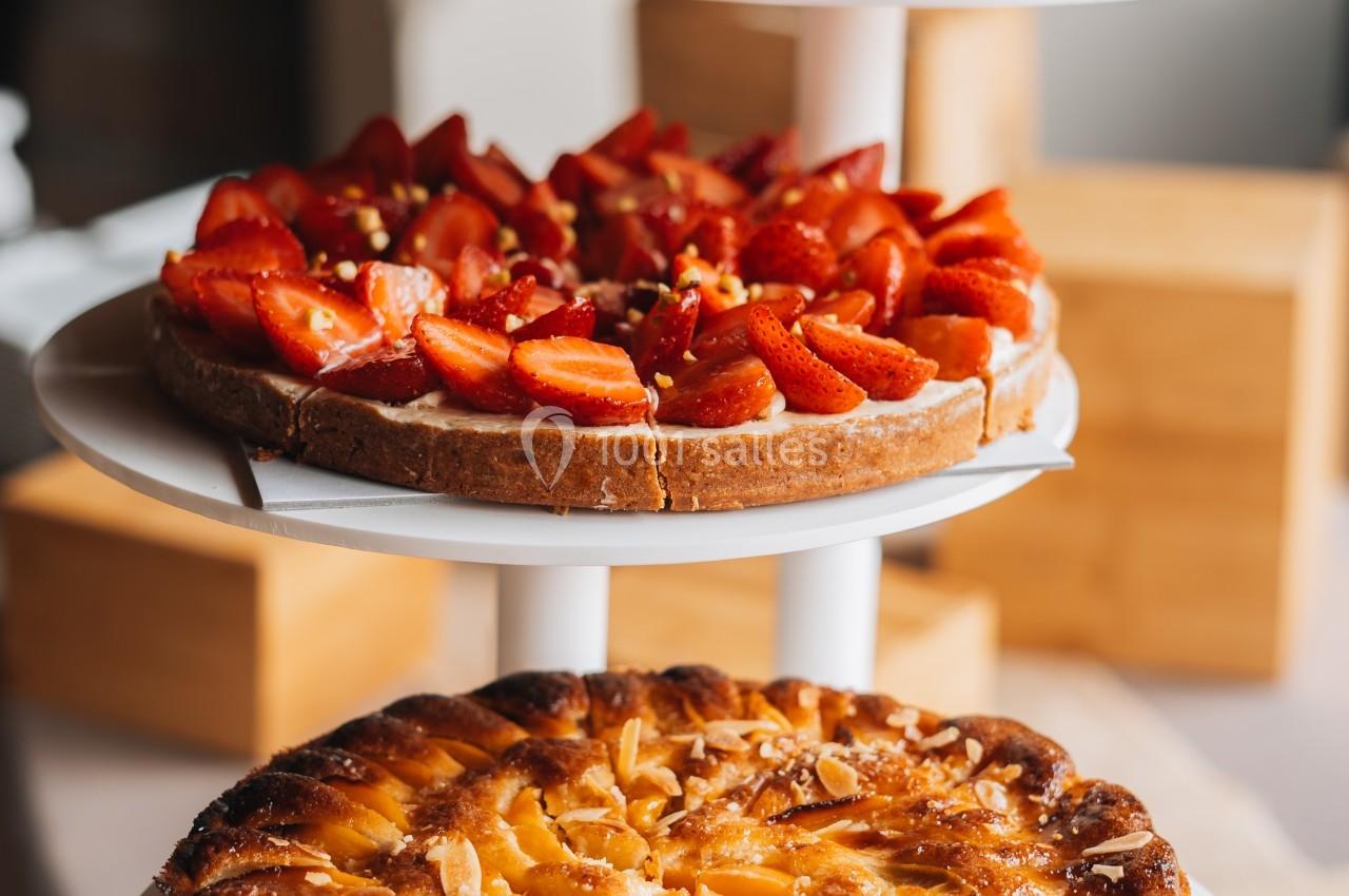 Trois tartes aux fruits, dont une aux fraises et une aux abricots, présentées sur des plateaux blancs empilés.