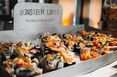 Personne utilisant une trancheuse rouge pour couper de la charcuterie dans un environnement professionnel.