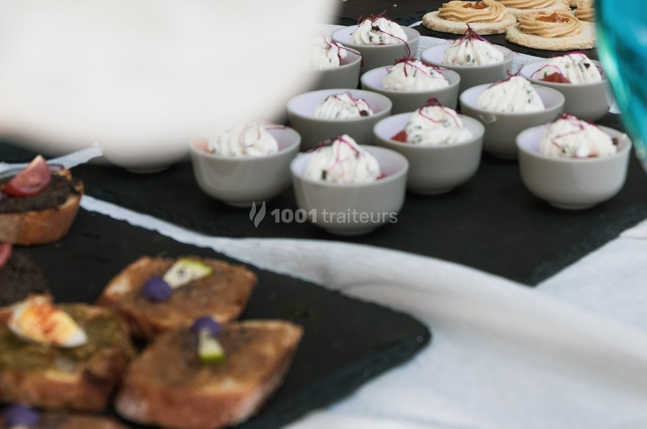 Assortiment de bouchées salées et verrines disposées sur des ardoises noires lors d'un buffet.