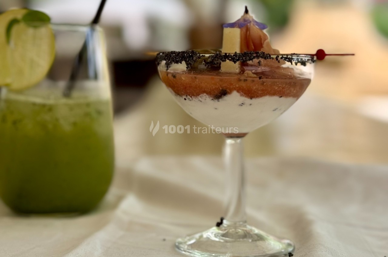 Dessert servi dans une coupe avec des couches de crème et fruits, accompagné d'un verre de boisson verte au citron.