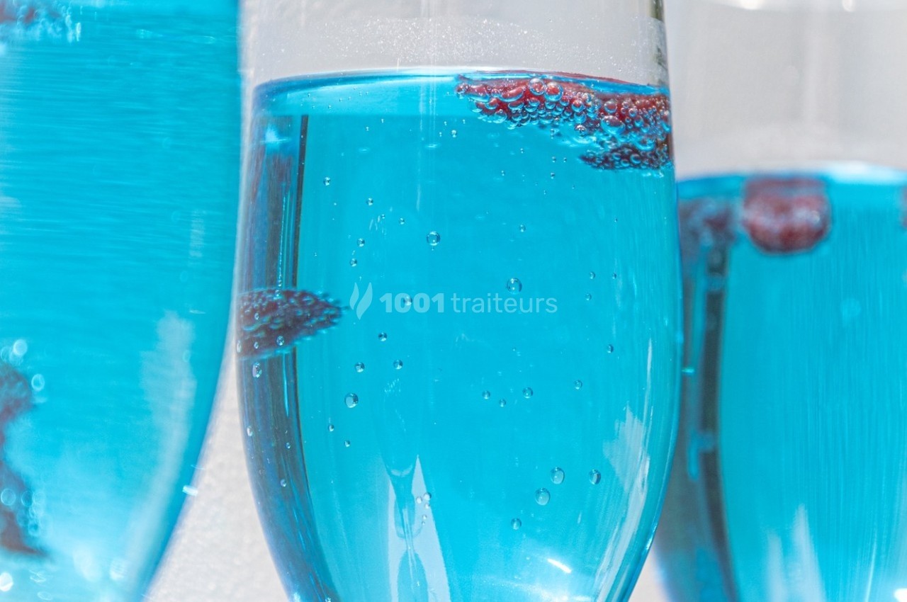 Verres remplis de liquide bleu pétillant avec des baies rouges flottant à la surface.