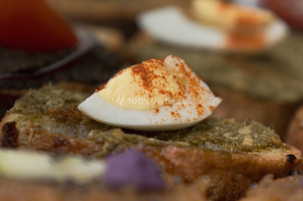 Tranche de pain garnie de tapenade, d'un quartier d'œuf dur et saupoudrée de paprika.