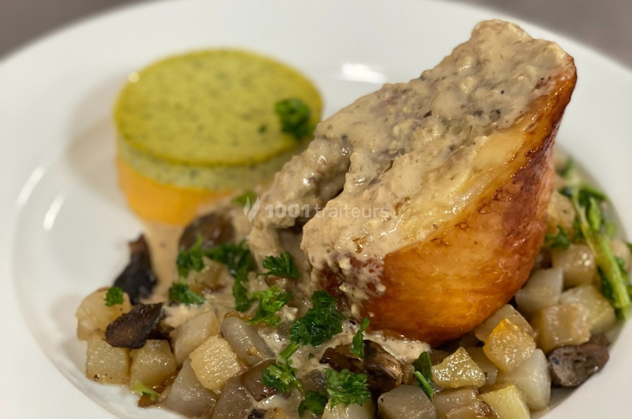 Plat composé d'une viande en sauce, servi avec des légumes sautés et un accompagnement cylindrique vert.