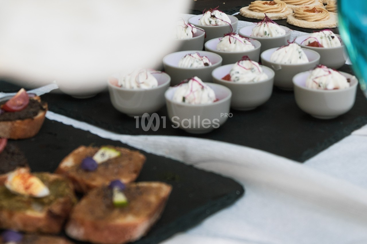Assortiment de bouchées salées et verrines disposées sur des ardoises noires lors d'un buffet.